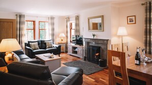 Un salon avec une cheminée, un canapé, un téléviseur et une table à manger avec des chaises.