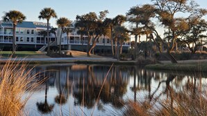 A serene lakeside view with a row of beachfront villas, reflecting the surrounding trees and sky.