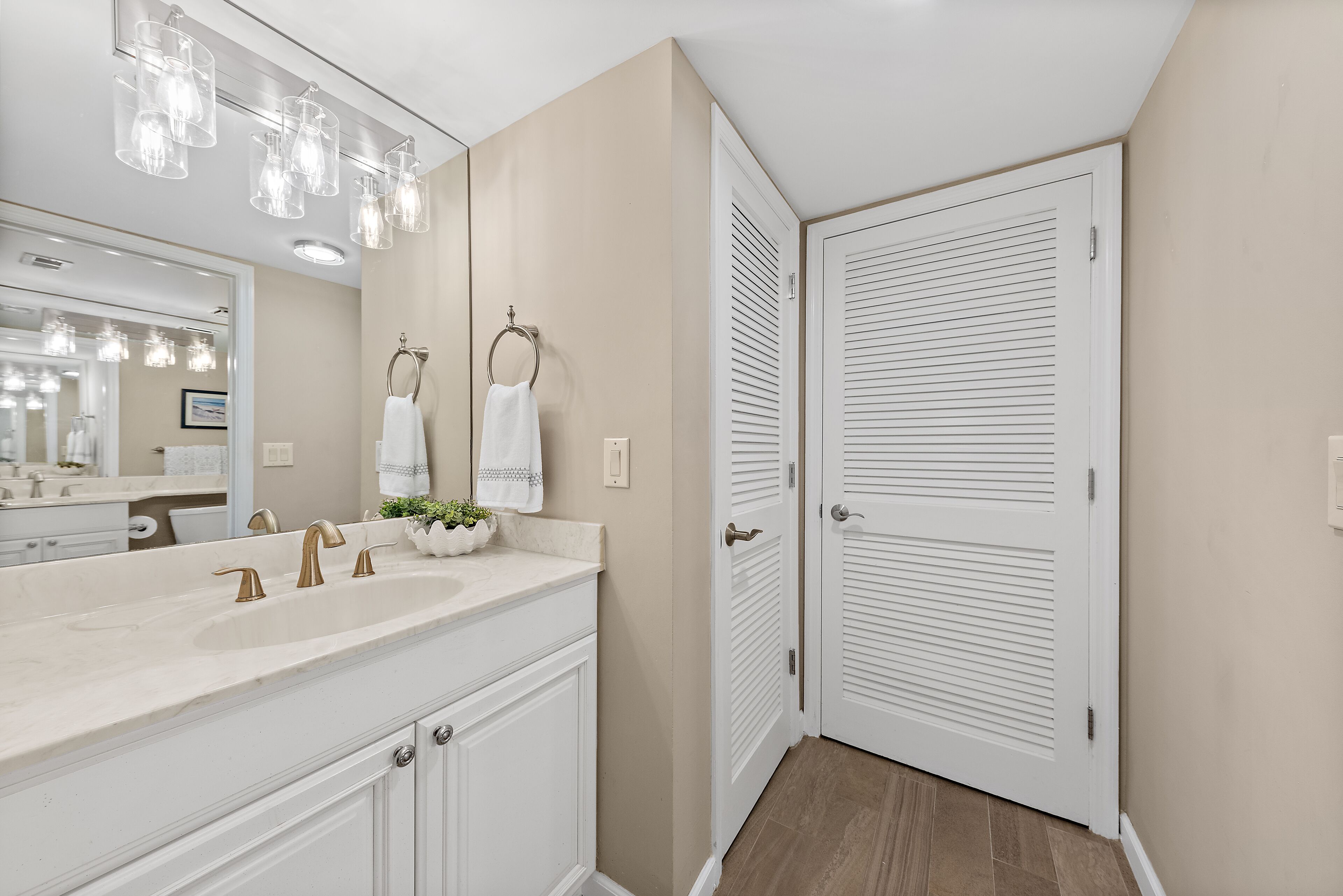 A bathroom with a large mirror, a sink with two faucets, and a towel ring.