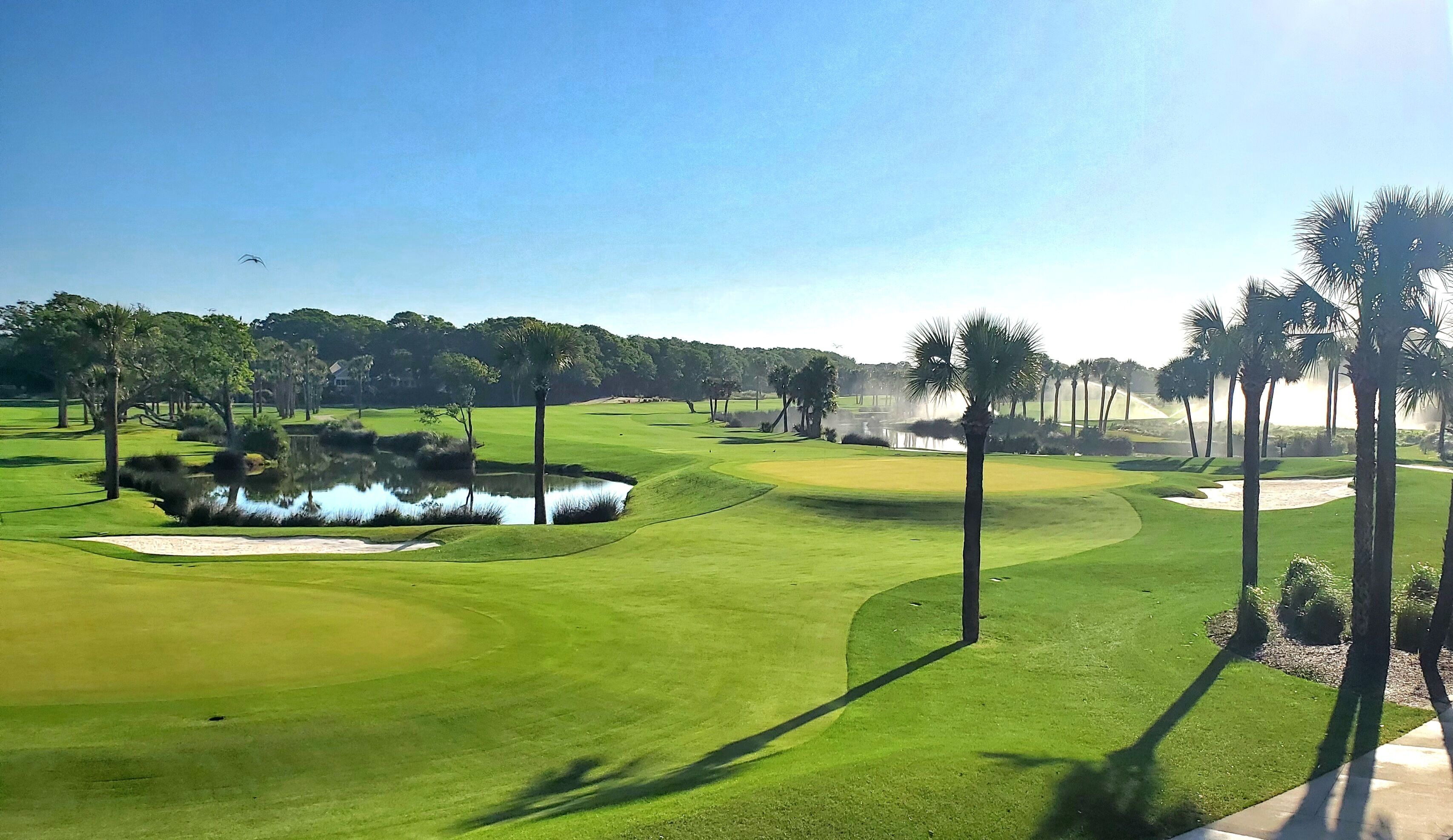 A golf course with sand bunkers, water hazards, and palm trees.
