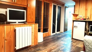 A modern kitchen with wooden cabinets, a built-in refrigerator, and a large window with blinds.