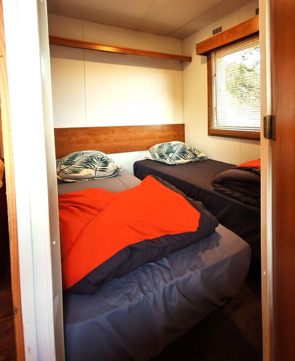 Une chambre de taille modeste, équipée de deux lits, chacun doté d’une t ête de lit en bois et d’oreillers assortis.
