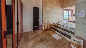 Hotellihuone, jossa on puinen katto, suuri ikkuna, pesuallas ja puinen tuoli.
