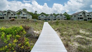 A wooden boardwalk leading to a row of beachfront buildings with balconies and large windows. - Beachfront 1BR/2BA Villa, Pet Friendly, Stunning Views, Amenity Access included (Seabrook Island)