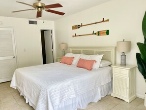 A bedroom with a bed, two bedside tables, a ceiling fan, and a door.
