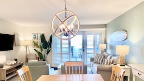 A spacious living room with a dining table, chairs, a sofa, and a TV. - Beachfront 1BR/2BA Villa, Pet Friendly, Stunning Views, Amenity Access included (Seabrook Island)