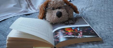 Un peluche con gli occhiali appoggiato su un libro.