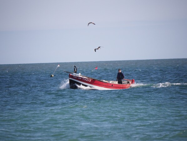 A small red and white boat named "MARY ANN" on the water with a person steering it.
