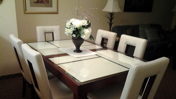 A dining table with white chairs, a vase of flowers, and a lamp on the side. - 25 ft. Balcony Oceanfront ! Incredible views !MONTHLY WINTER RENTAL AVAILABLE ! (Myrtle Beach)