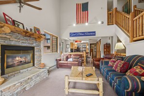 A living room with a stone fireplace, a wooden coffee table, a blue sofa, and a flag.