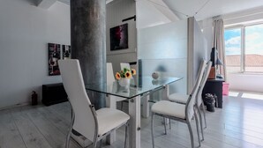 A modern dining area with a glass table, white chairs, and a vase with flowers. - Acropolis front row loft,please watch video (Athens)