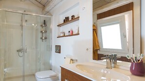 A bathroom with a glass shower enclosure, a white toilet, a vanity with a sink, and shelves above the mirror. - Splendid apartment with terrace overlooking Corso Umberto, Taormina, Sycily (Taormina)