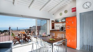 A modern kitchen with an orange refrigerator, a dining area with a table and chairs, and a view of the sea. - Splendid apartment with terrace overlooking Corso Umberto, Taormina, Sycily (Taormina)