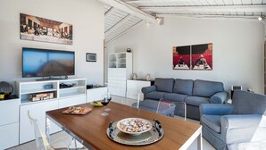 A modern living room with a dining area, a television, and artwork on the walls. - Splendid apartment with terrace overlooking Corso Umberto, Taormina, Sycily (Taormina)