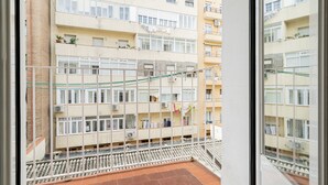A multi-story residential building with balconies, visible laundry hanging, and a tiled floor.