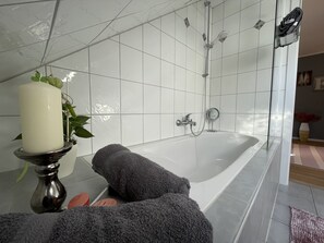 Een bad/douchecombinatie, een haardroger, handdoeken, zeep