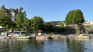 A lakeside dock with several boats, a building with a red roof, and a large tree in the background. - Modern apartment in Schauenstein with loggia and balcony **** (Schauenstein)