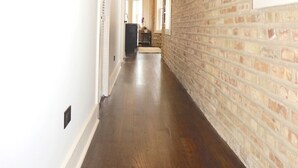 Un pasillo largo y estrecho con suelo de madera y paredes de ladrillo.