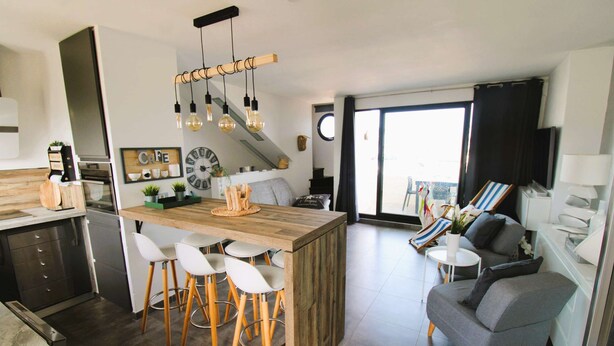 A modern kitchen with a central island, bar stools, and a dining area with a sofa and chairs. - Apartment for 6 people, air-conditioned, with a view of the port at the Marines de Cogolin (COGOLIN)