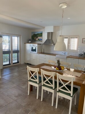 Una cocina moderna con armarios blancos, una mesa de comedor de madera y una lámpara colgante.