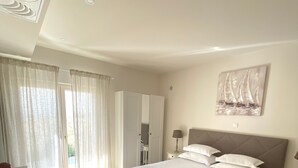 Ein Schlafzimmer mit einem großen Bett, einem Kleiderschrank, einem Schreibtisch und einem Bild an der Wand.
