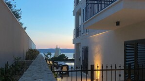 Ein steinbelagter Weg führt zu einem Balkon mit einem Tor, der auf ein Gewässer blickt.