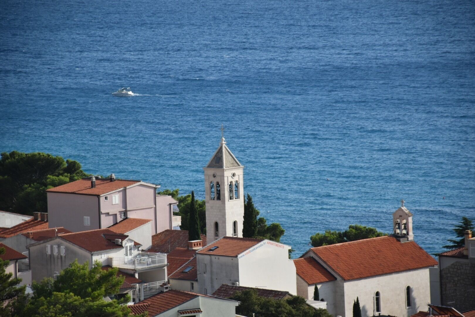 A coastal town with a prominent church tower, terraced buildings, and a view of the sea.