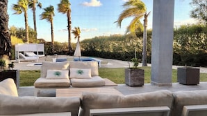 Un espace aménagé au bord de la piscine, comprenant des chaises longues, une petite piscine et des palmiers.