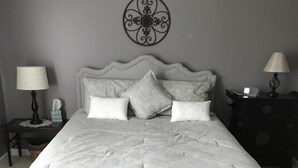 Une chambre avec un grand lit, un banc en bois, deux tables de chevet et un élément décoratif mural.