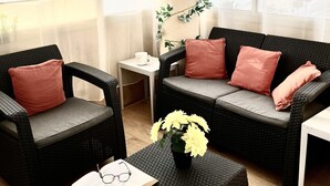 A cozy seating area with wicker furniture, a small table with a book and glasses, and a vase with flowers. - FRANCE NICE PROMENADE OF ENGLISH 80 m2 PIANO    (Nice)