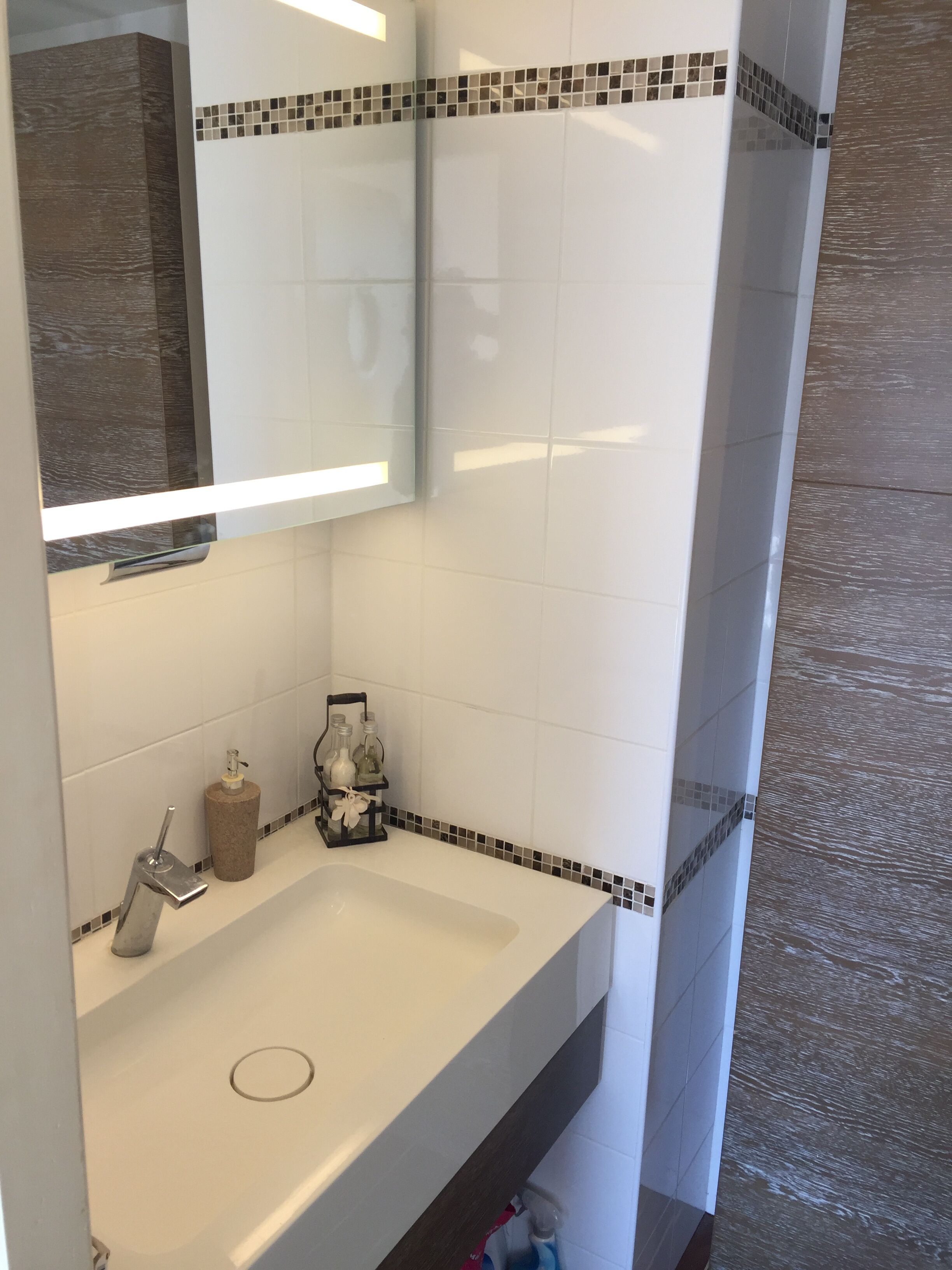 A bathroom with a white sink, a mirror, and a tiled backsplash.