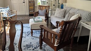 Una sala acogedora con una silla de madera, un sofá a rayas y una mesita pequeña.