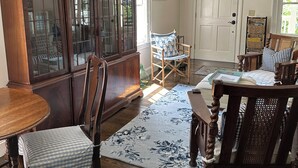Un salón tradicional con una mesa de comedor de madera, sillas, un mueble grande de madera y una alfombra floral.