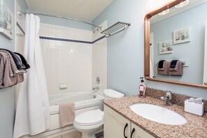 Baño con ducha, inodoro, lavamanos y toallero.