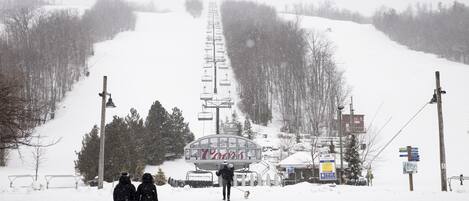 A snow-covered ski lift with people walking towards it.