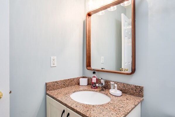 A bathroom with a granite countertop, white sink, and a large mirror with a wooden frame.