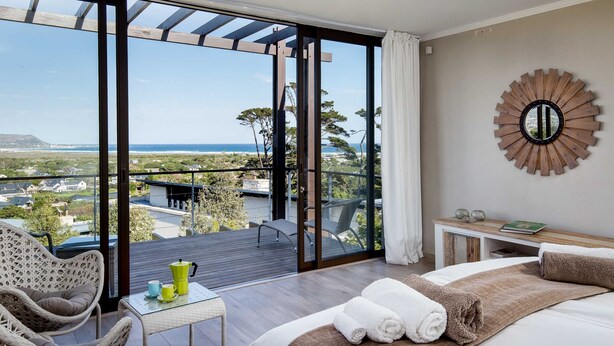 Ein Schlafzimmer mit einer großen Schiebeglasdoor, die auf einen Balkon mit Blick auf das Meer und die umliegende Landschaft führt.
