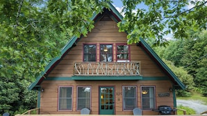 A cabin with a balcony, two Adirondack chairs, and a grill on the deck. - Cabin near BR/Boone, fire pit, WIFI, secluded, nearby hikes, and VIEWS!! (Blowing Rock)