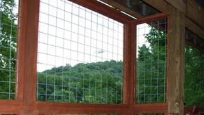 Un jacuzzi con estructura de madera y grandes ventanales, que ofrece vistas a una colina boscosa.
