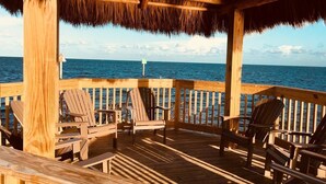 A wooden deck with chairs and a table, overlooking the ocean. - Ocean view condo with balcony/marina view (Tavernier)