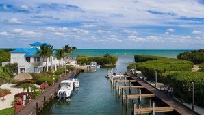 A marina with boats docked, a waterway, and a building with blue roofs. - Ocean view condo with balcony/marina view (Tavernier)