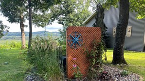 A garden area with a wooden fence, a metal gate, and a star-shaped metal decoration. - Chippewa View Heights ~ breathtaking views and a peaceful getaway! (Durand)
