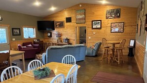 A cozy, wood-paneled room with a dining area, seating, and a bar sign indicating the bar is open. - Chippewa View Heights ~ breathtaking views and a peaceful getaway! (Durand)