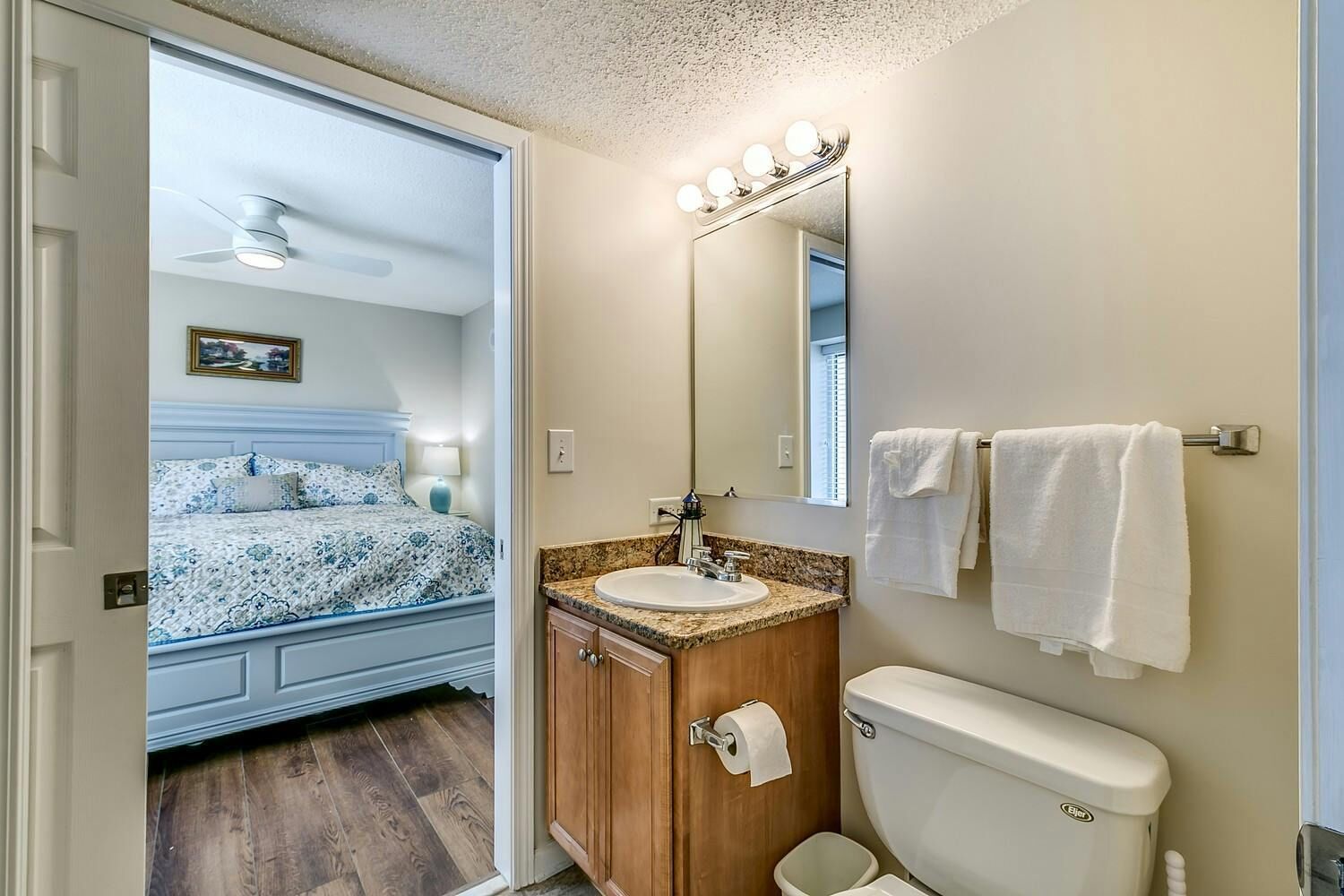 Une chambre à coucher avec un lit, une salle de bain avec un lavabo, un miroir et des toilettes.