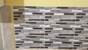 Una cocina con estufa a gas, salpicadero de azulejos y pared amarilla.