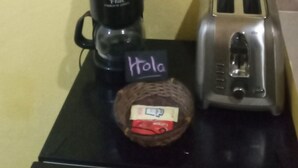 Una encimera de cocina con cafetera, tostadora y una cesta de pan.