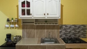 Una cocina con armarios blancos, un fregadero, una estufa y una encimera.