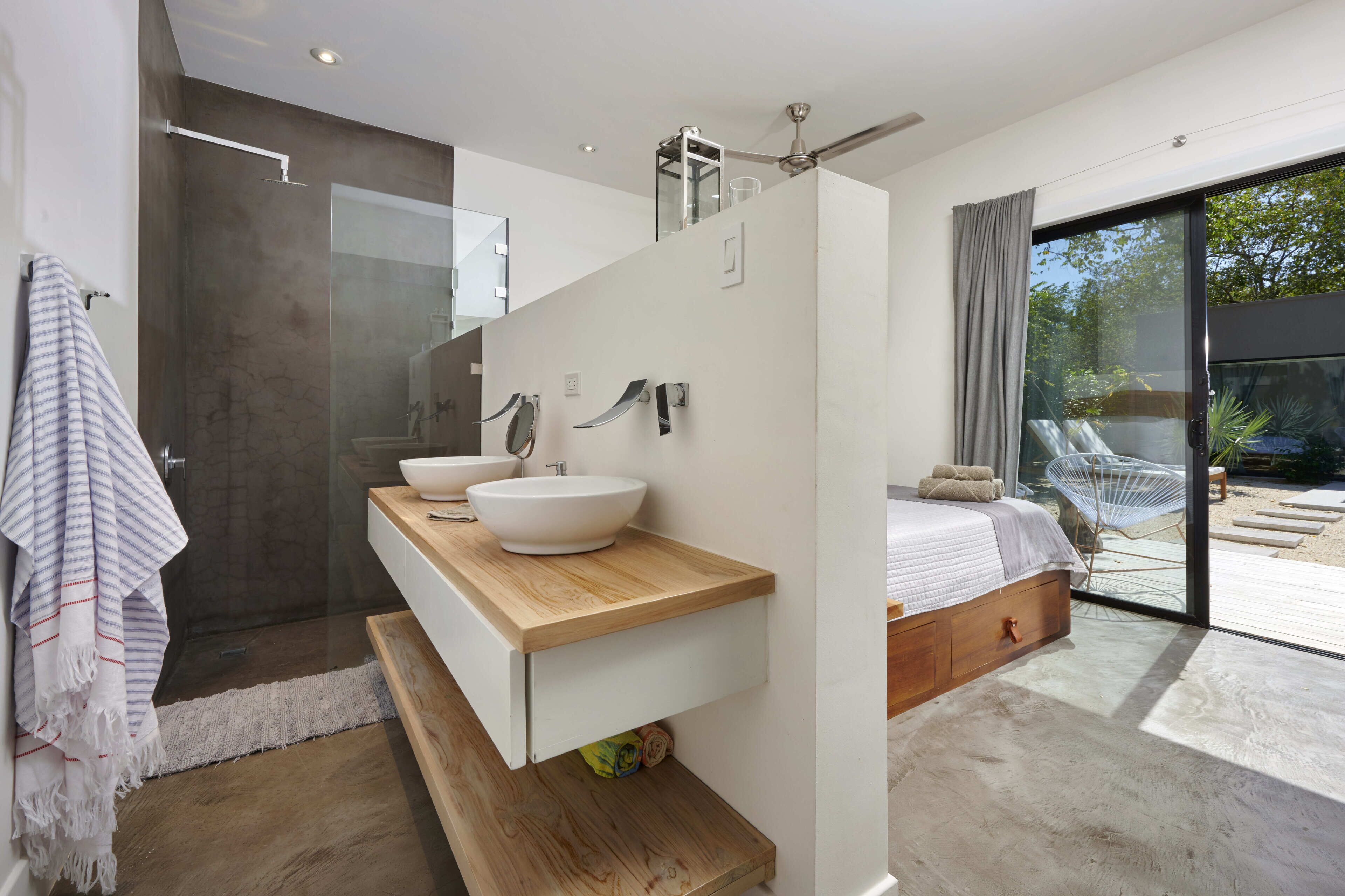 A modern bathroom with a large mirror, two sinks, and a shower.