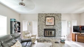 Una sala de estar con chimenea de piedra, sofá de cuero y televisión.
