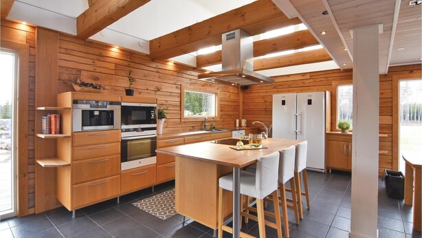 A modern kitchen with wooden paneling, built-in appliances, and a central island with bar stools. - Beautiful home in Aneby with WiFi (Aneby)
